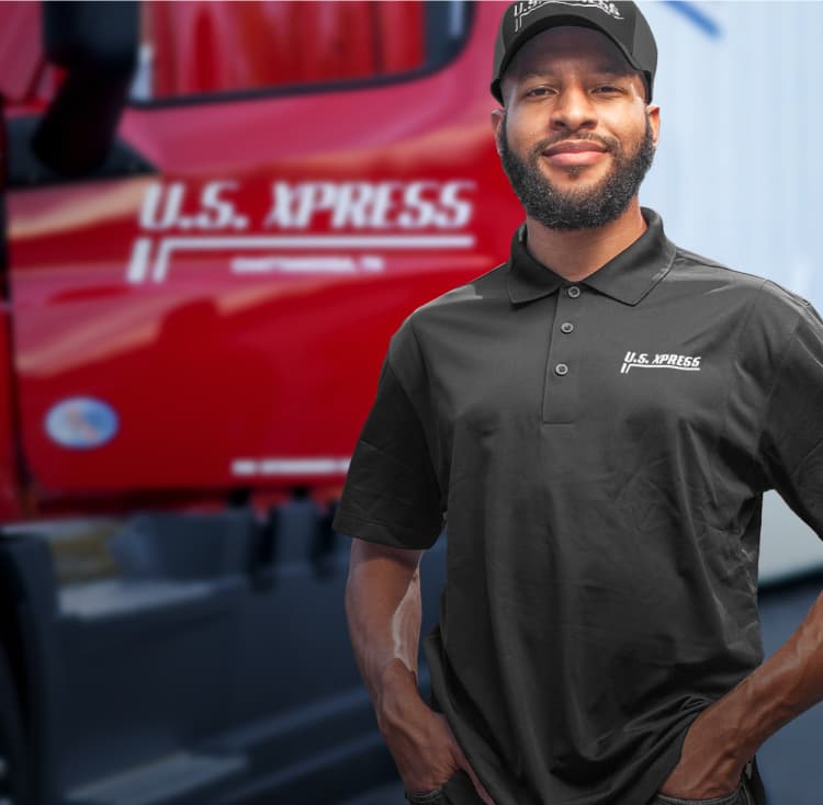 African-American driver wearing a black U.S. Xpress branded shirt is standing confidently in front of his red, U.S. Xpress truck.